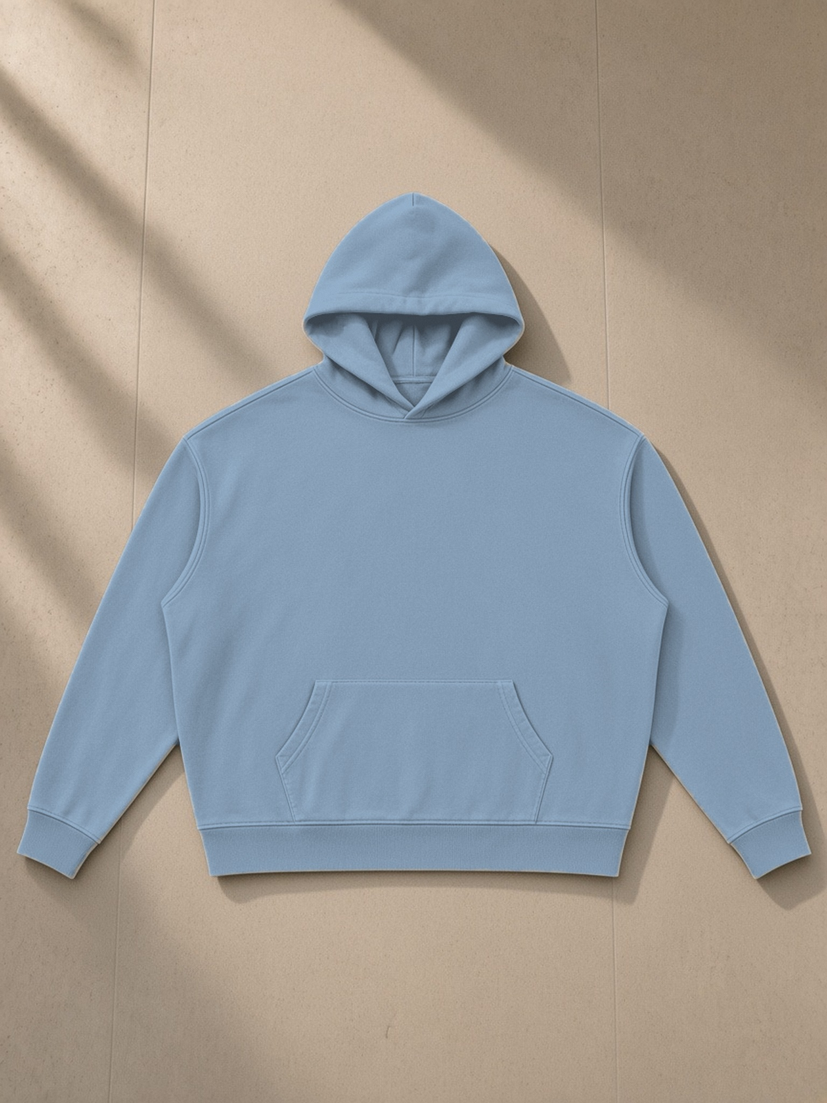 Vintage Wash Boxy Hoodie in Jeans Blue, laid flat on pale limestone, front.