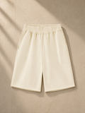 Raw edge fleece shorts in Apricot, laid flat on pale limestone