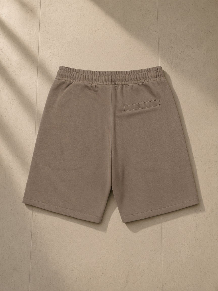 Essential Cotton Shorts in Coffee, laid flat on pale limestone, back view