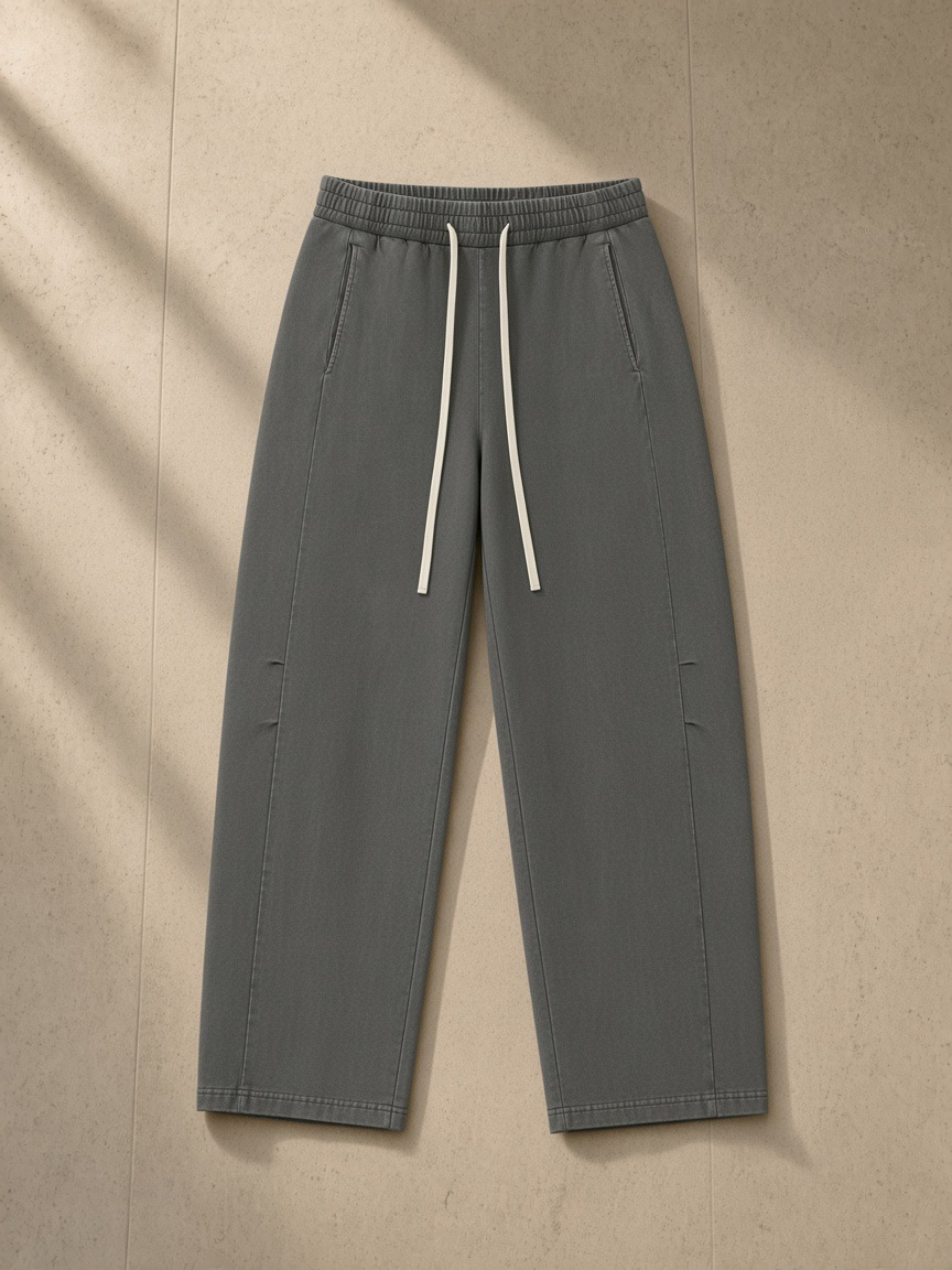 Unisex mineral wash barrel leg pants in Dark Gray, laid flat on pale limestone