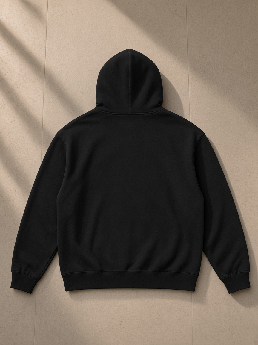 Men's heavyweight full-zip hoodie in Black, laid flat on pale limestone, back view