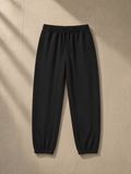 Women's Loose Fit Tapered Joggers in Black, laid flat on pale limestone
