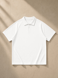 Unisex regular fit polo shirt in White, laid flat on pale limestone