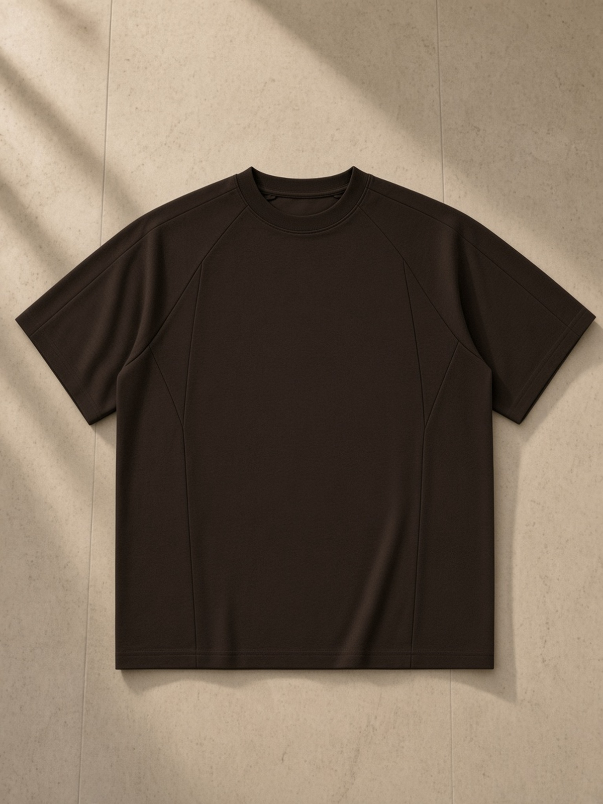 Oversized Paneled Raglan T-Shirt in Brown, laid flat on pale limestone, front.