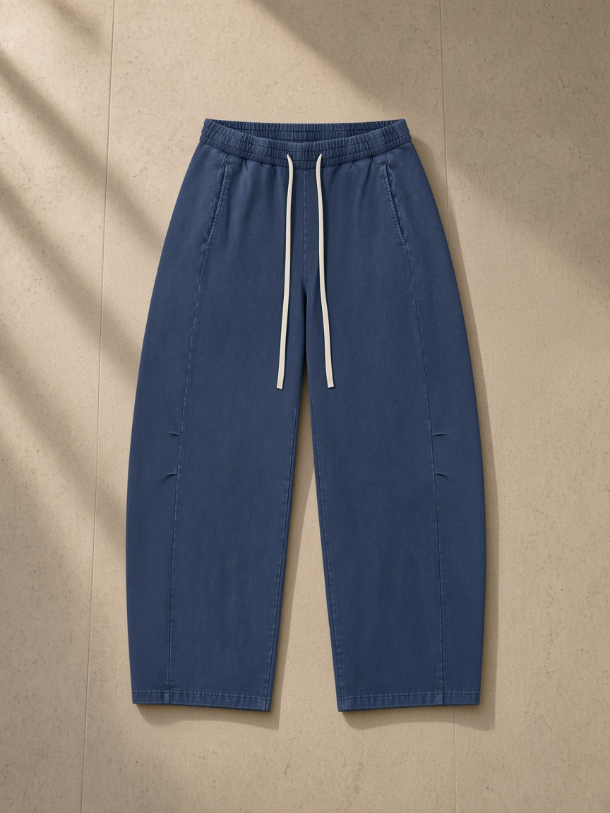 Unisex mineral wash barrel leg pants in Blue, laid flat on pale limestone
