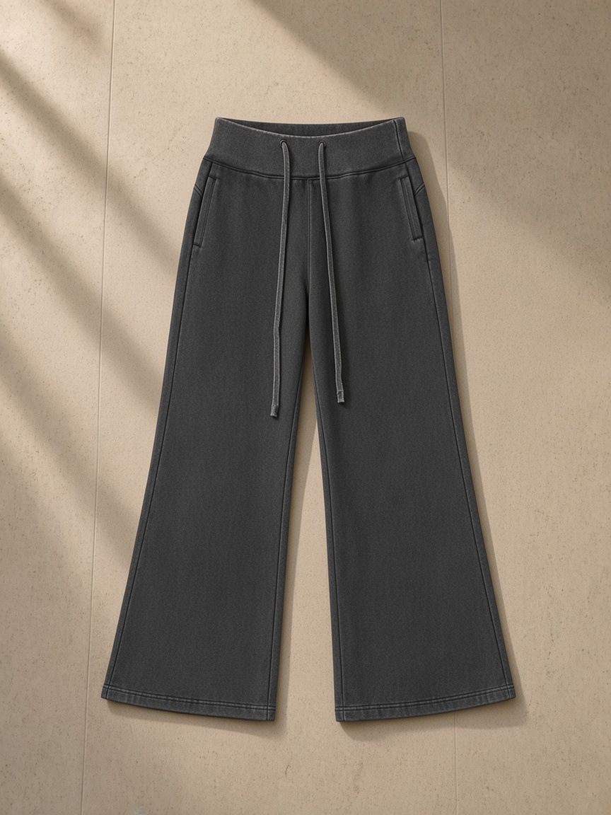 Vintage washed flared fleece pants in Washed Black, laid flat on pale limestone