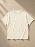 Heavyweight Knit Round Neck T-Shirt in Apricot, laid flat on pale limestone
