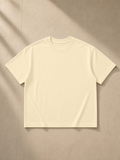 Unisex boxy drop shoulder t-shirt in Apricot, laid flat on pale limestone