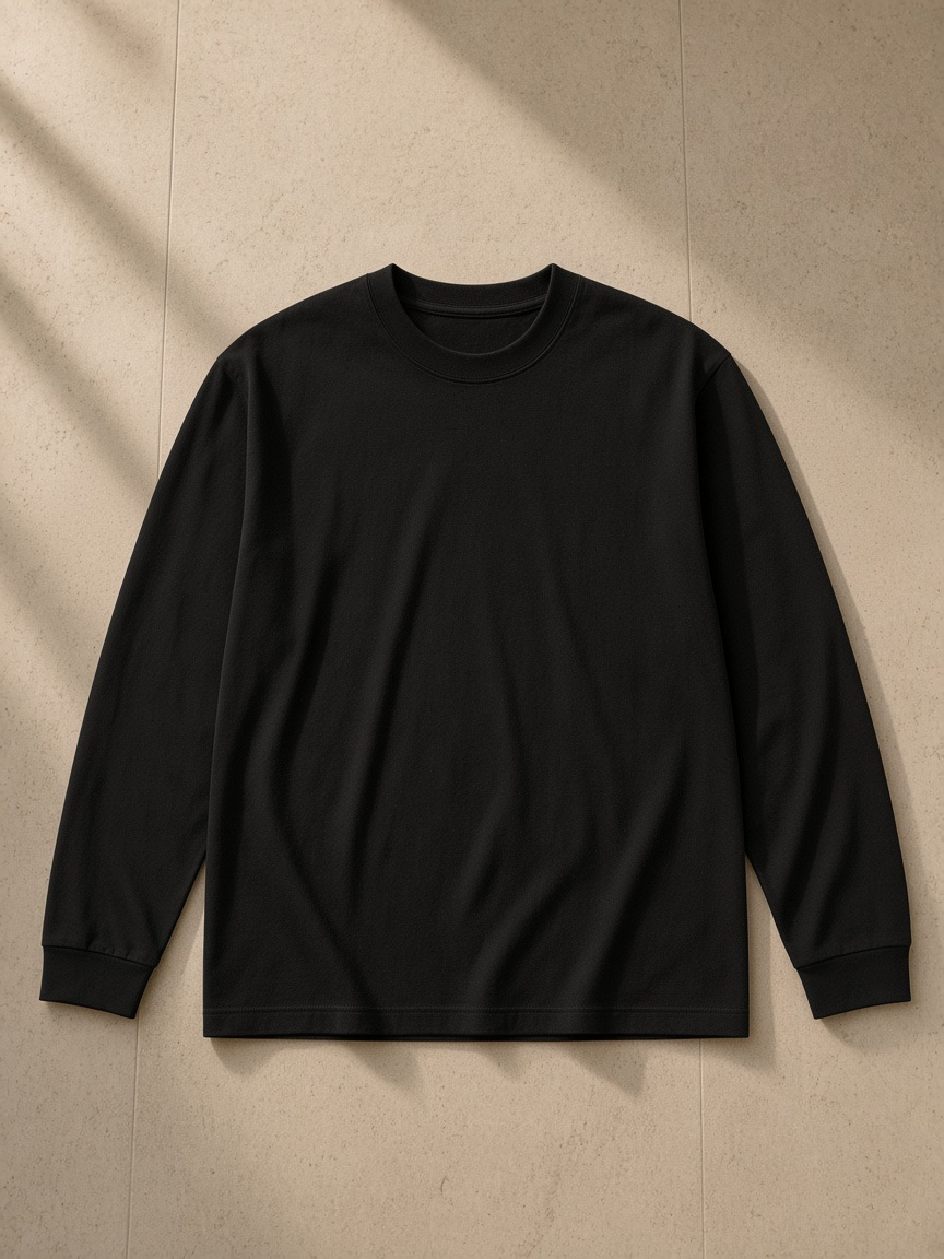 Crew neck drop shoulder long sleeve shirt in Black, laid flat on pale limestone