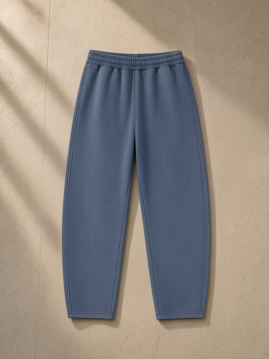 Vintage wash barrel leg fleece sweatpants in Washed Blue, laid flat on pale limestone