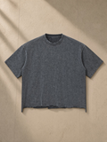 Unisex snow wash raw-hem boxy t-shirt in Washed Cement Gray, laid flat on pale limestone