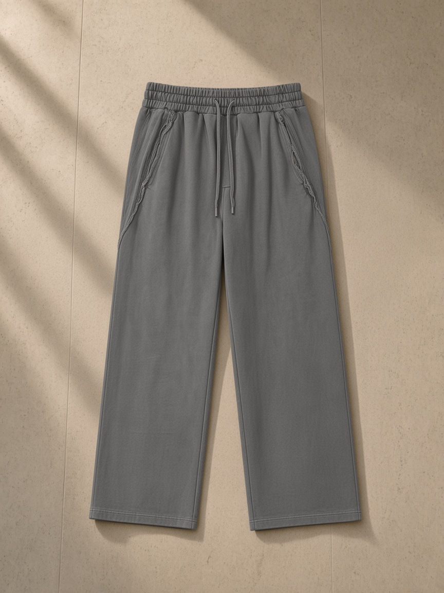 Snow Washed Tape Raw Edge Sweatpants in Dark Gray, laid flat on pale limestone, front.