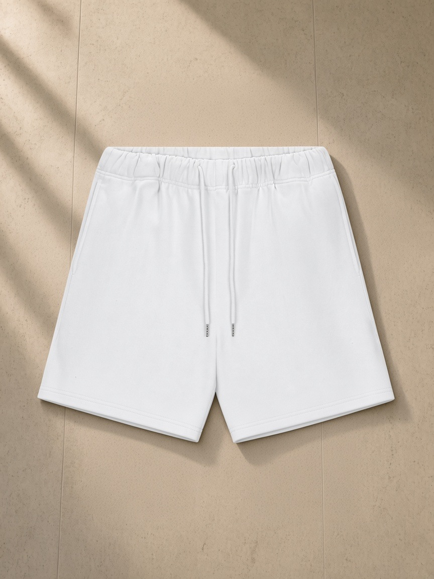 Heavyweight fleece loose fit shorts in Lucent White, laid flat on pale limestone