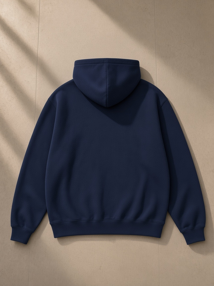 Unisex oversized heavyweight hoodie in Navy Blue folded on a turned-down linen bed in a Lake Como villa at night