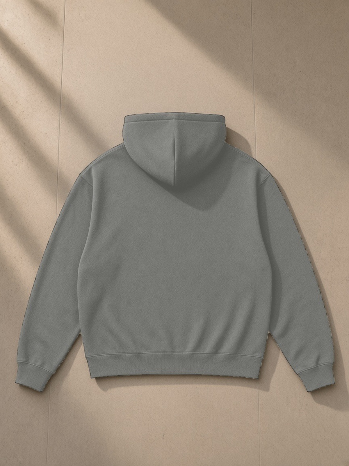 Essential Heavyweight Drop-Shoulder Hoodie in Dark Gray, laid flat on pale limestone, back view