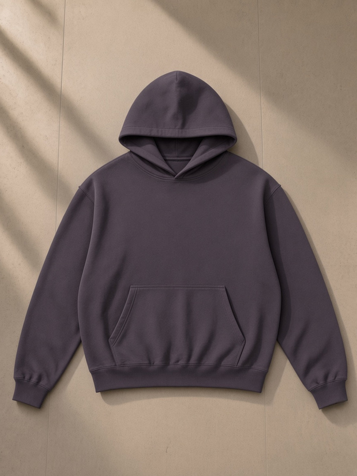 Unisex boxy darted sleeve hoodie in Plum Purple, laid flat on pale limestone, front view