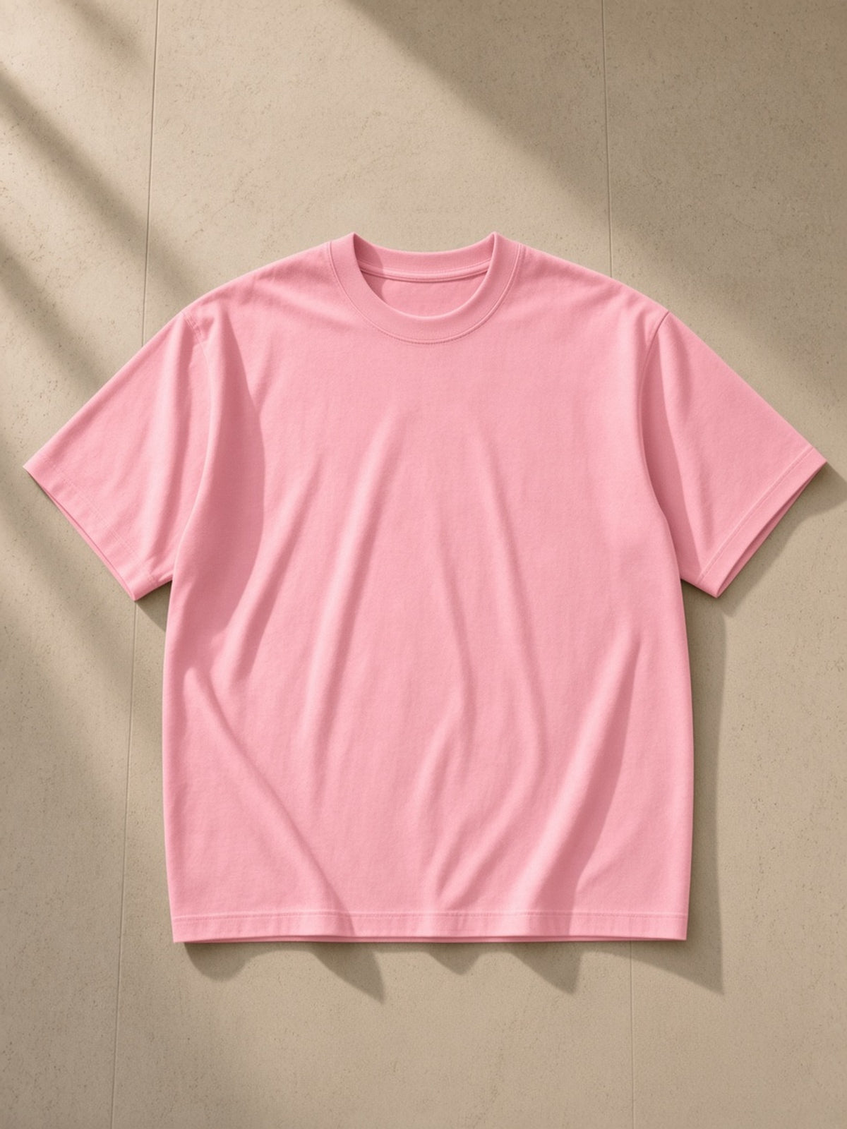 Loose fit crewneck t-shirt in Pink, laid flat on pale limestone