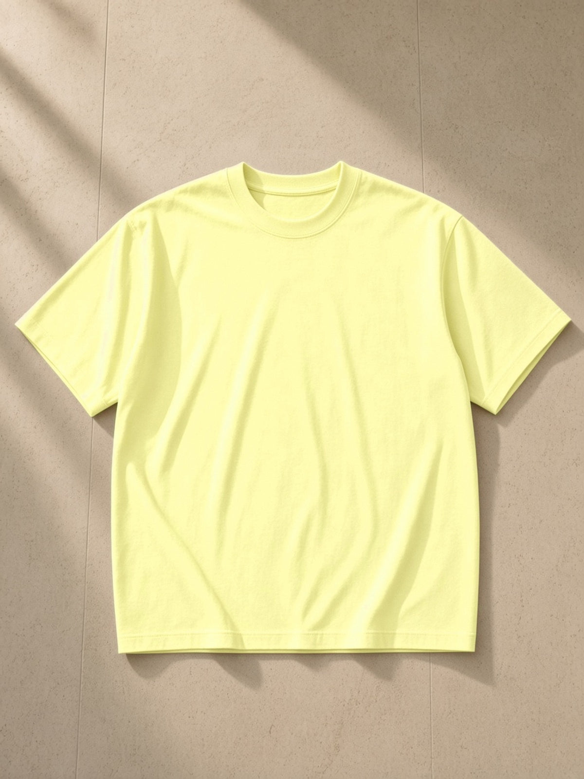 Loose fit crewneck t-shirt in Yellow, laid flat on pale limestone