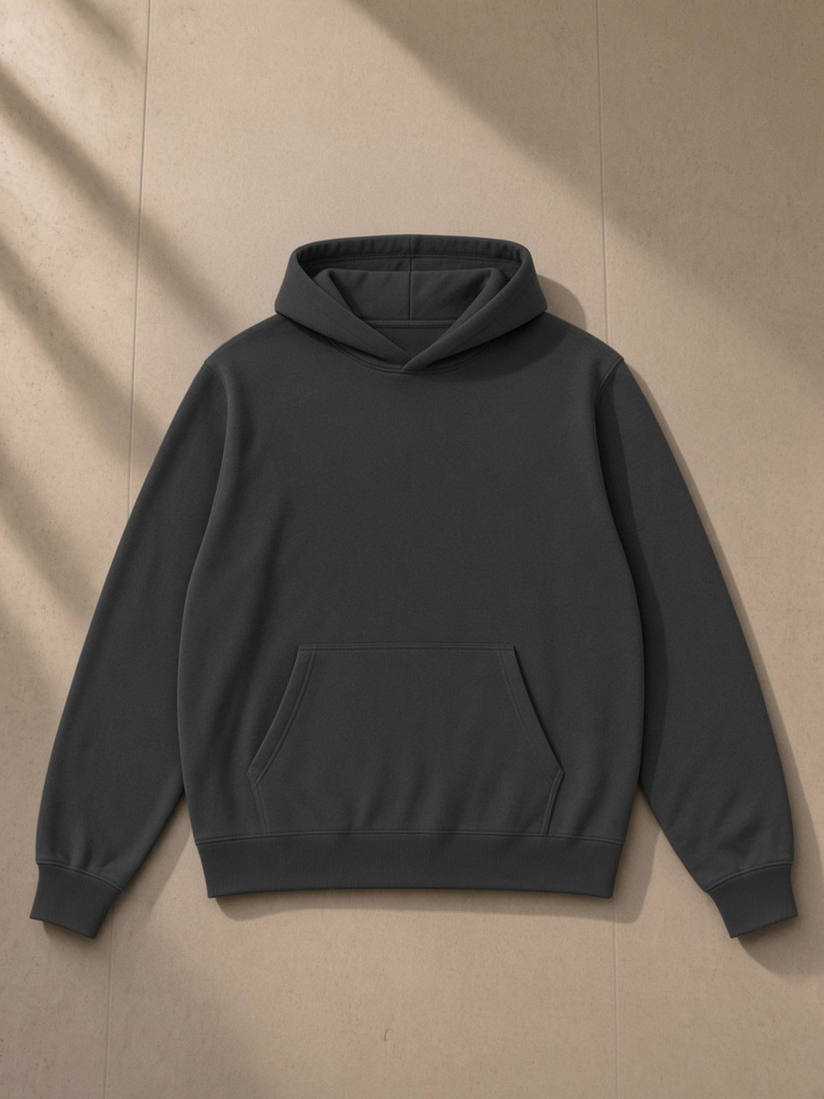 Unisex fleece regular shoulder hoodie in Dark Gray, laid flat on pale limestone, front view