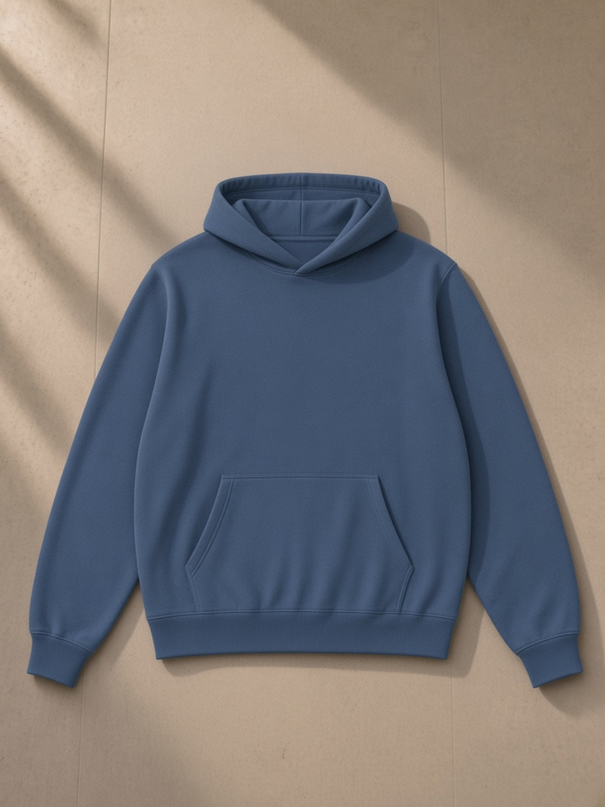 Unisex fleece regular shoulder hoodie in Haze Blue, laid flat on pale limestone, front view