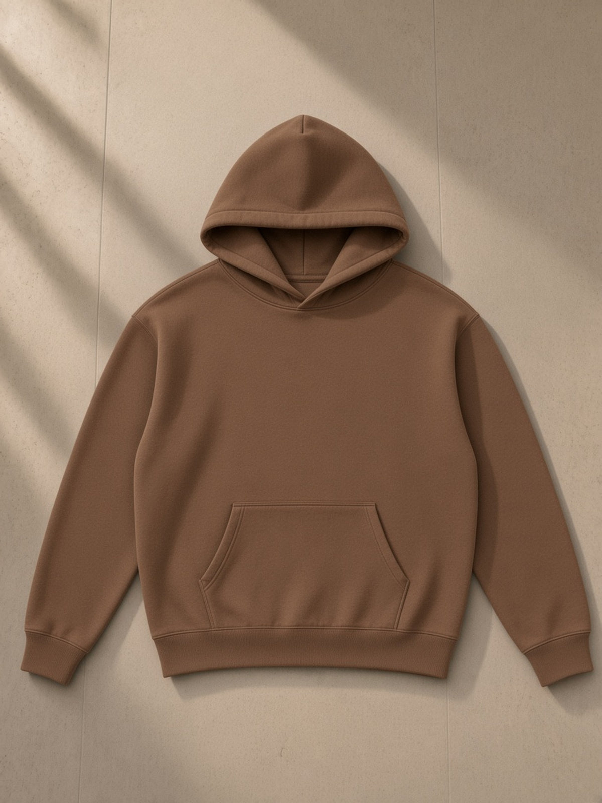 Oversize fleeced hoodie in Brown, laid flat on pale limestone