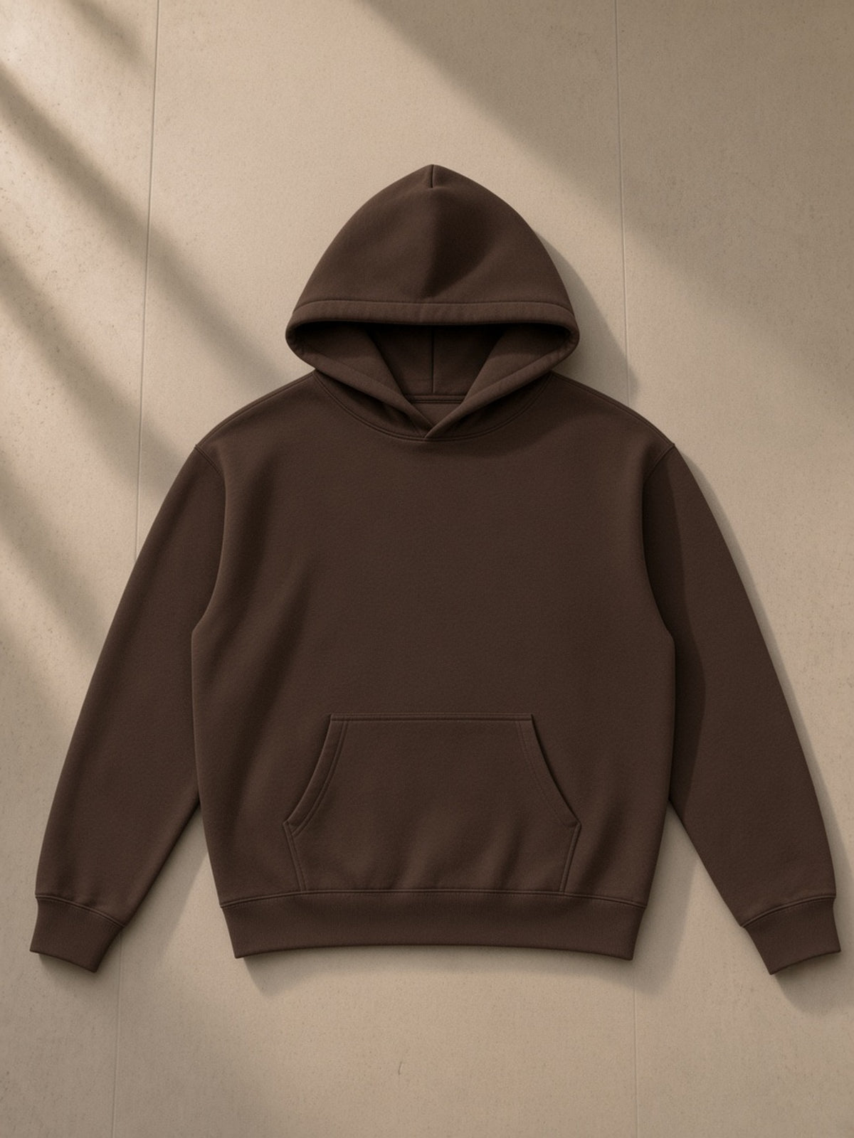 Oversize fleeced hoodie in Coffee, laid flat on pale limestone