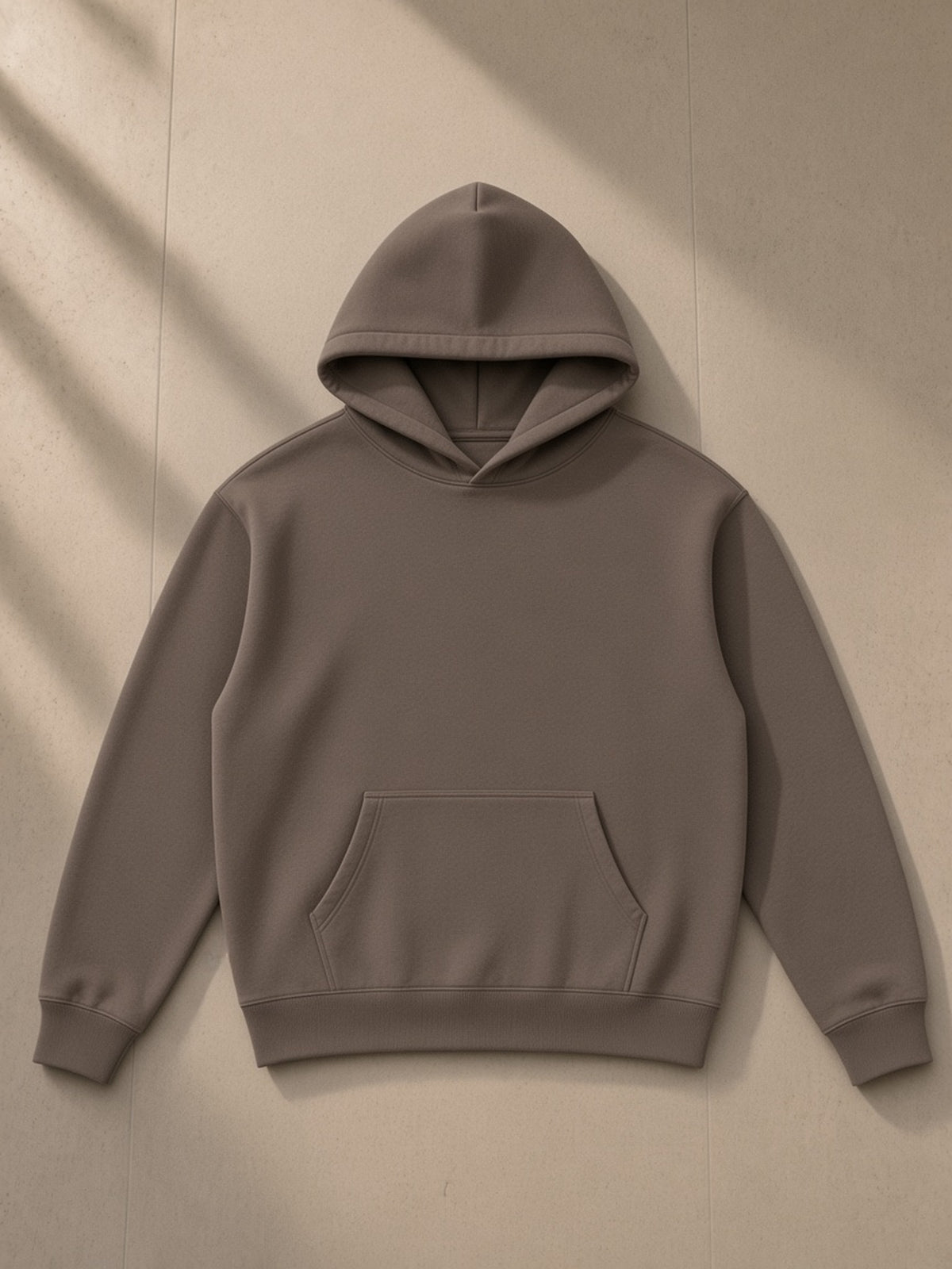 Oversize fleeced hoodie in Dark Brown, laid flat on pale limestone