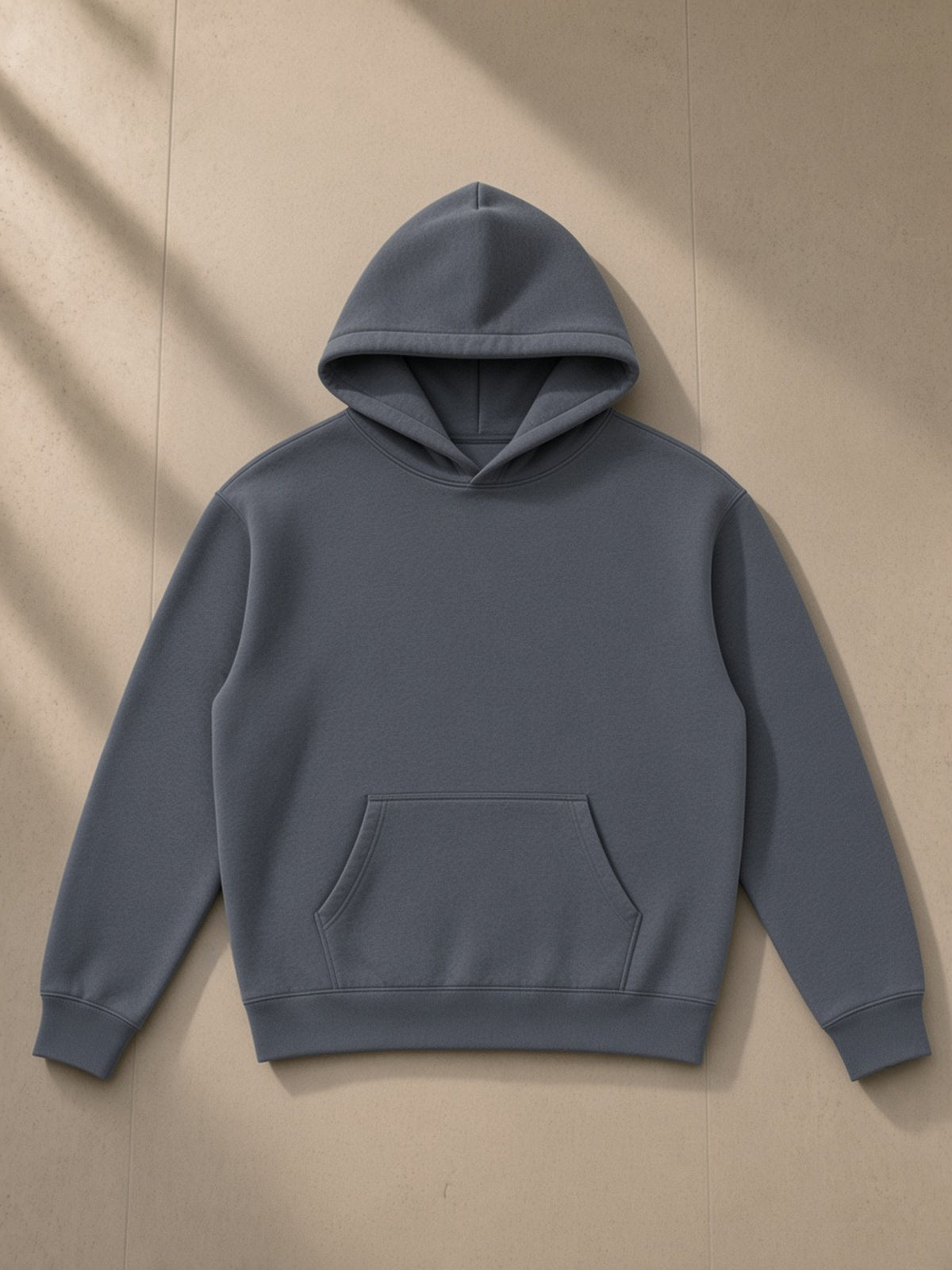 Oversize fleeced hoodie in Gray Blue, laid flat on pale limestone