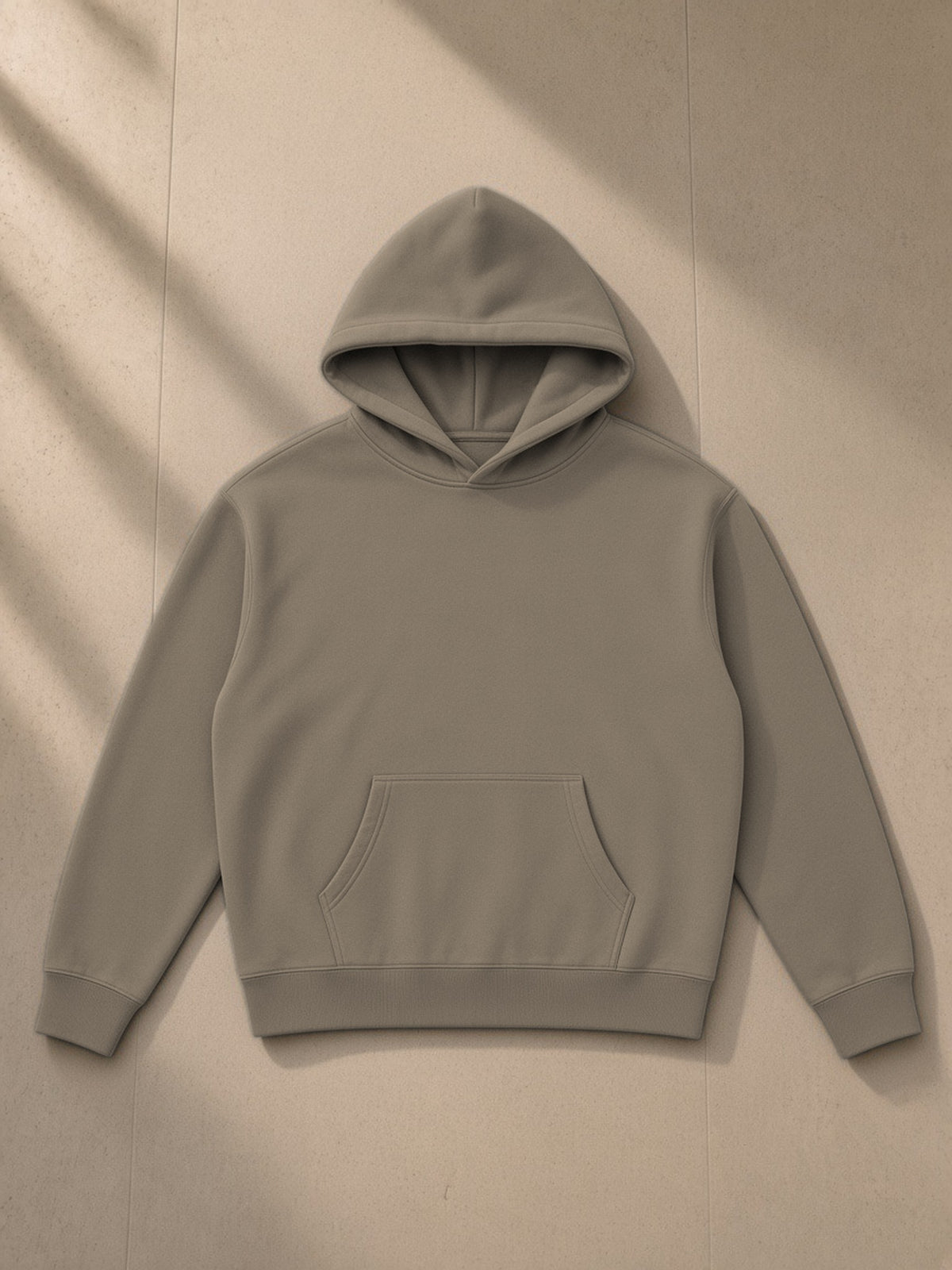 Oversize fleeced hoodie in Gray Coffee, laid flat on pale limestone