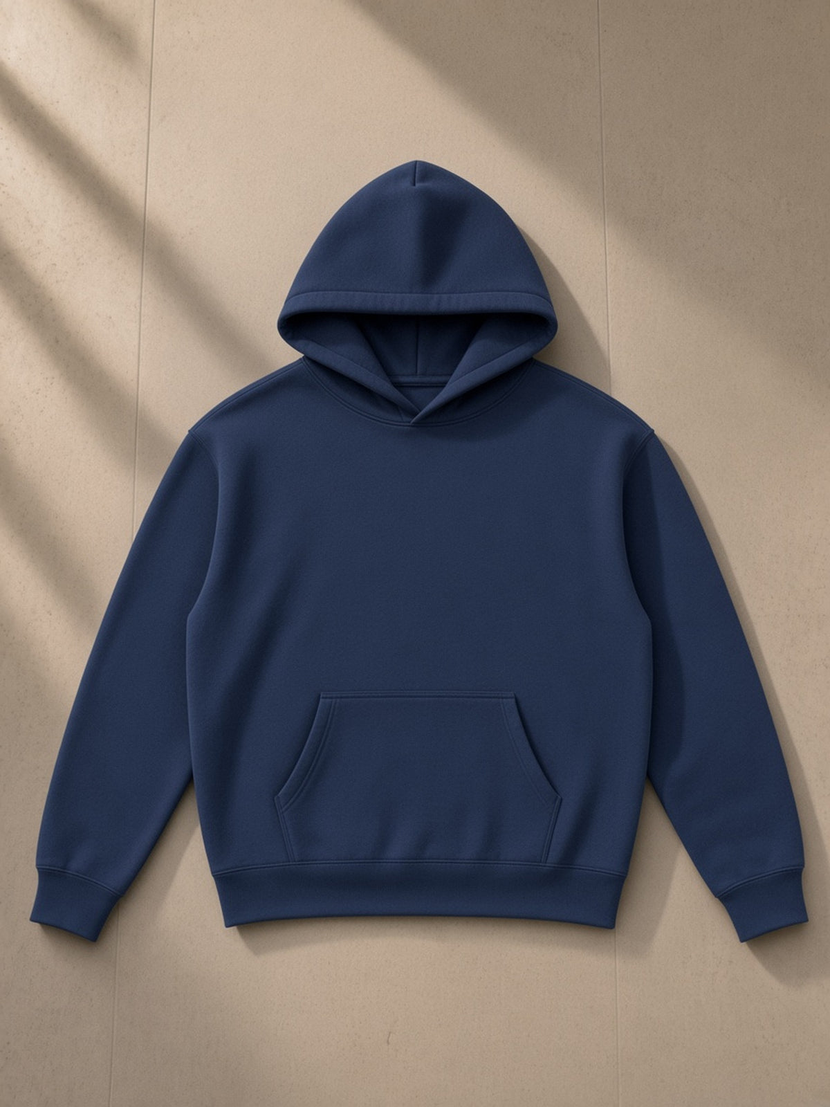 Oversize fleeced hoodie in Navy Blue, laid flat on pale limestone