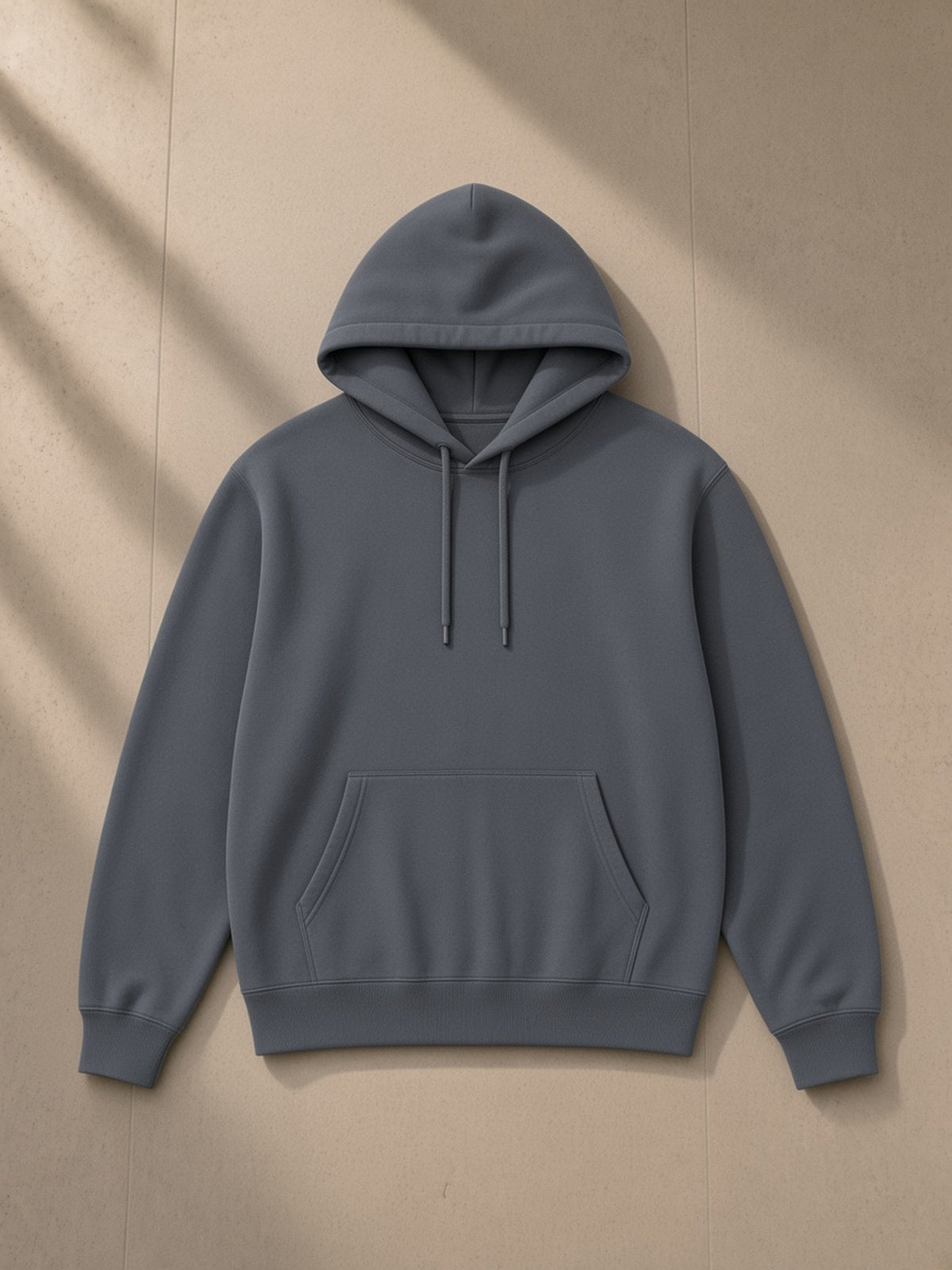 Unisex classic cotton hoodie in Dark Grey, laid flat on pale limestone