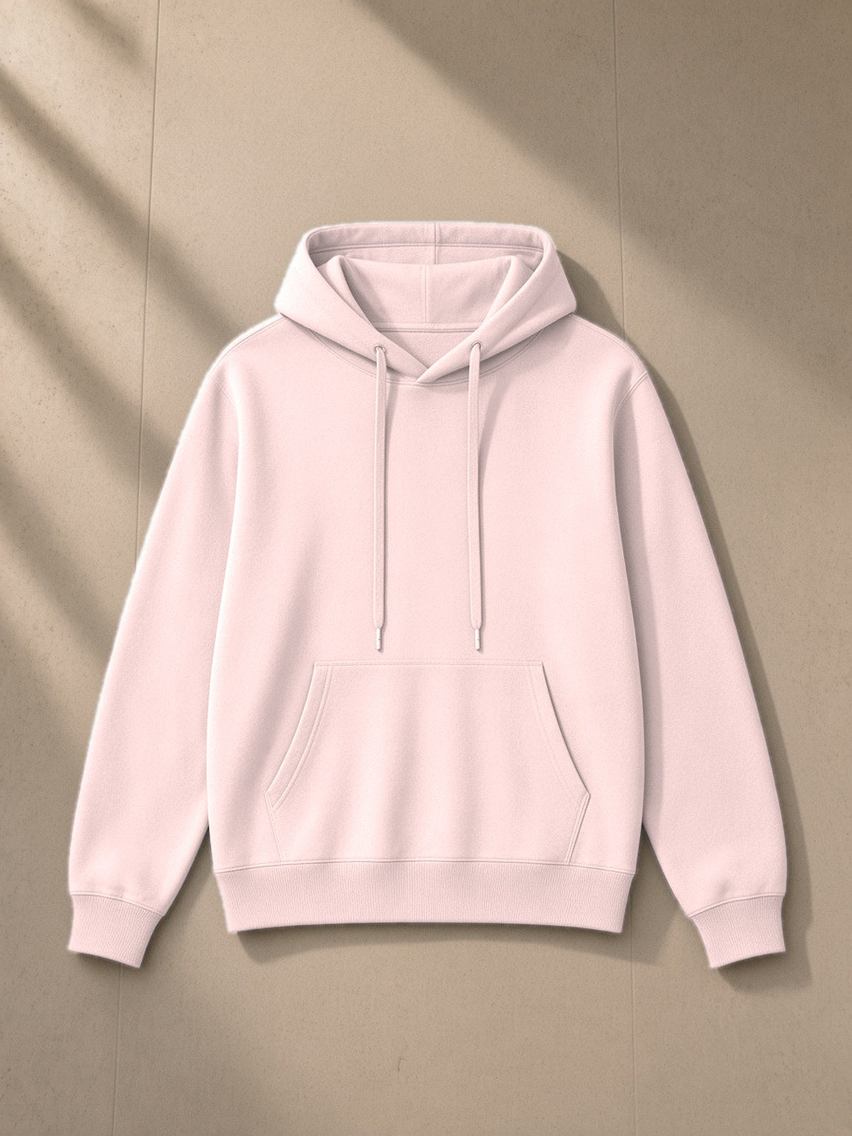 Unisex classic cotton hoodie in Light Pink, laid flat on pale limestone