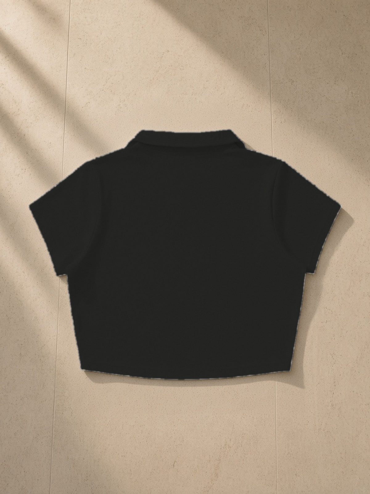V-Neck Lapel Crop Top in Black, laid flat on pale limestone, back view