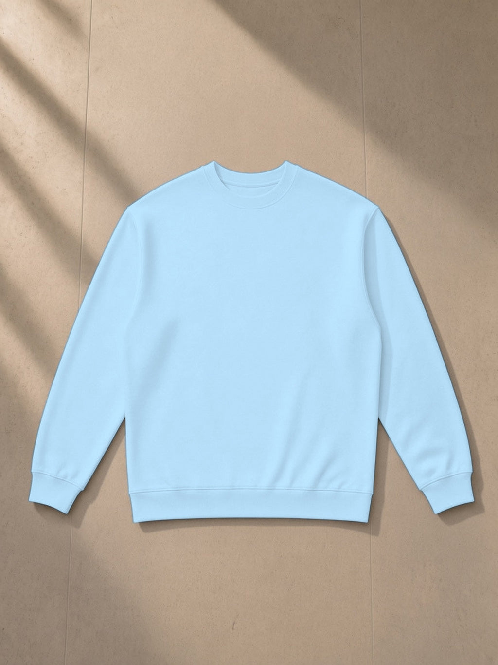 Oversized Crewneck Sweatshirt in Light Blue, laid flat on pale limestone, front view