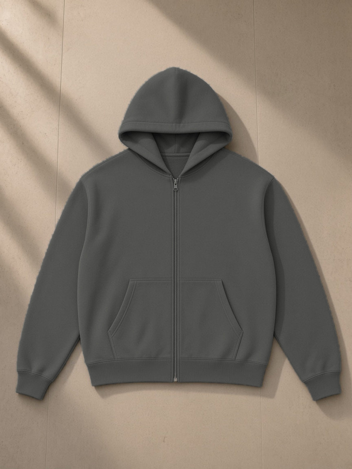 Essential fleece zip-through hoodie in Dark Gray, laid flat on pale limestone, front view
