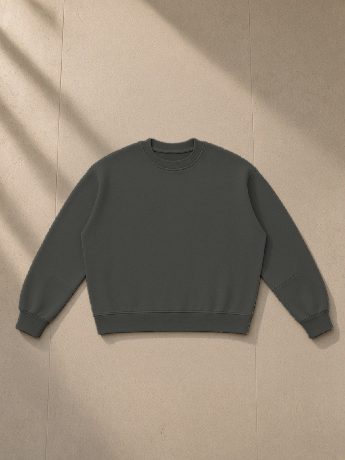 Boxy Vintage Washed Sweatshirt in Dark Gray, laid flat on pale limestone, front view