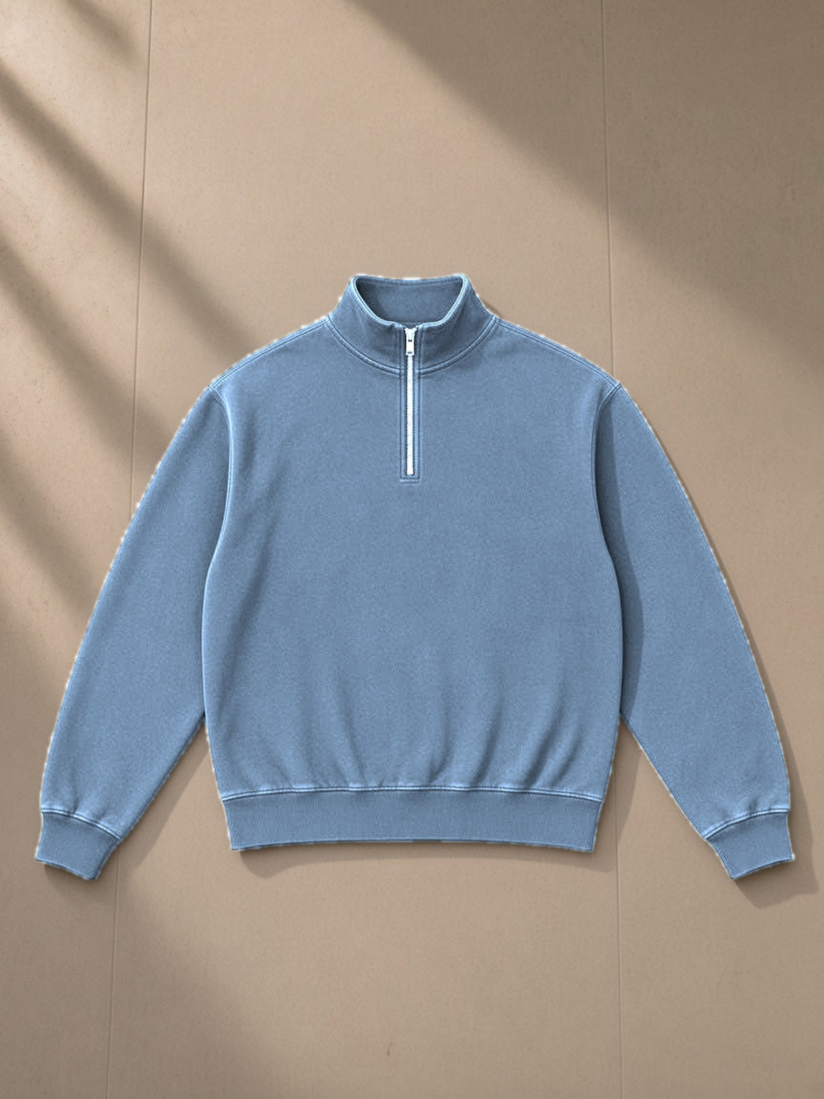 Unisex vintage wash fleece quarter zip sweatshirt in Blue, laid flat on pale limestone, front view