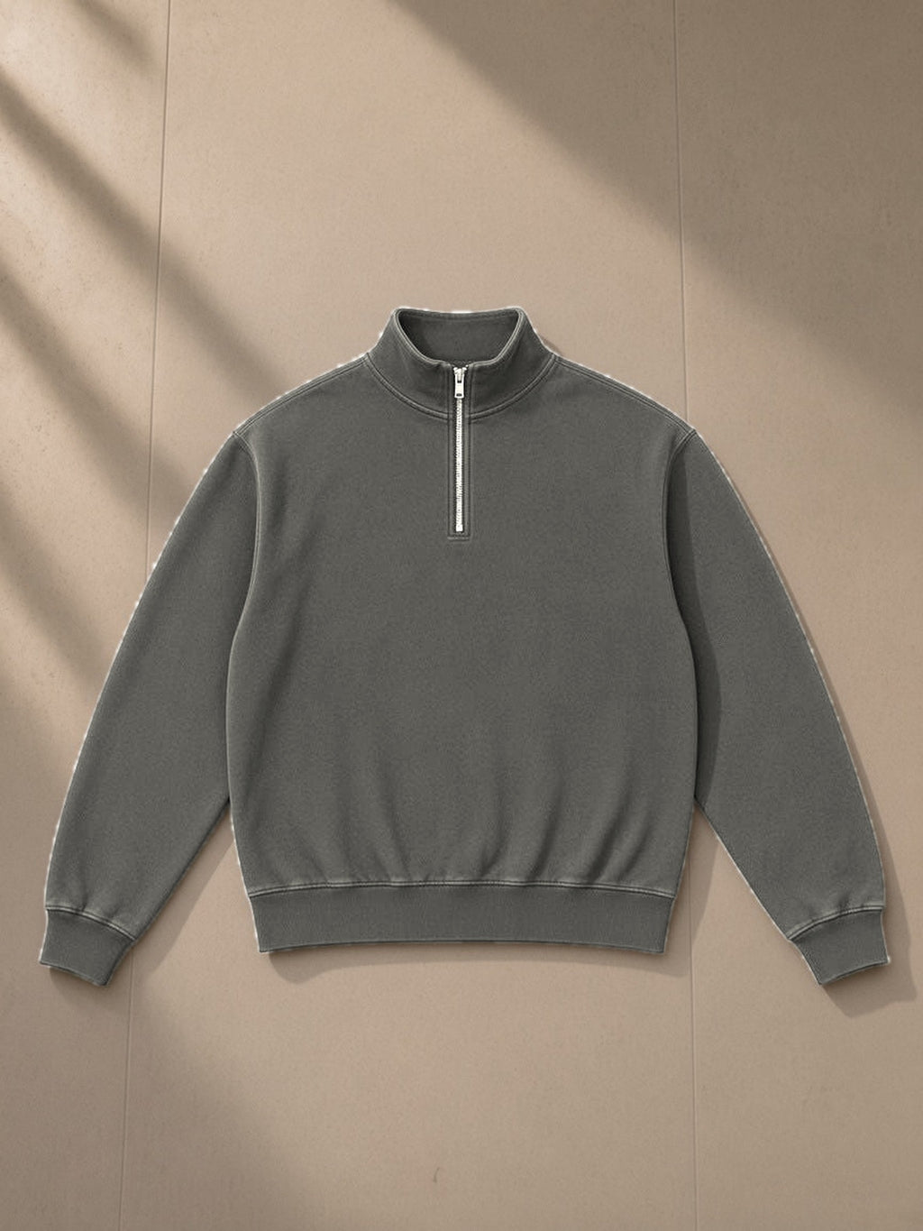 Unisex vintage wash fleece quarter zip sweatshirt in Gray, laid flat on pale limestone, front view
