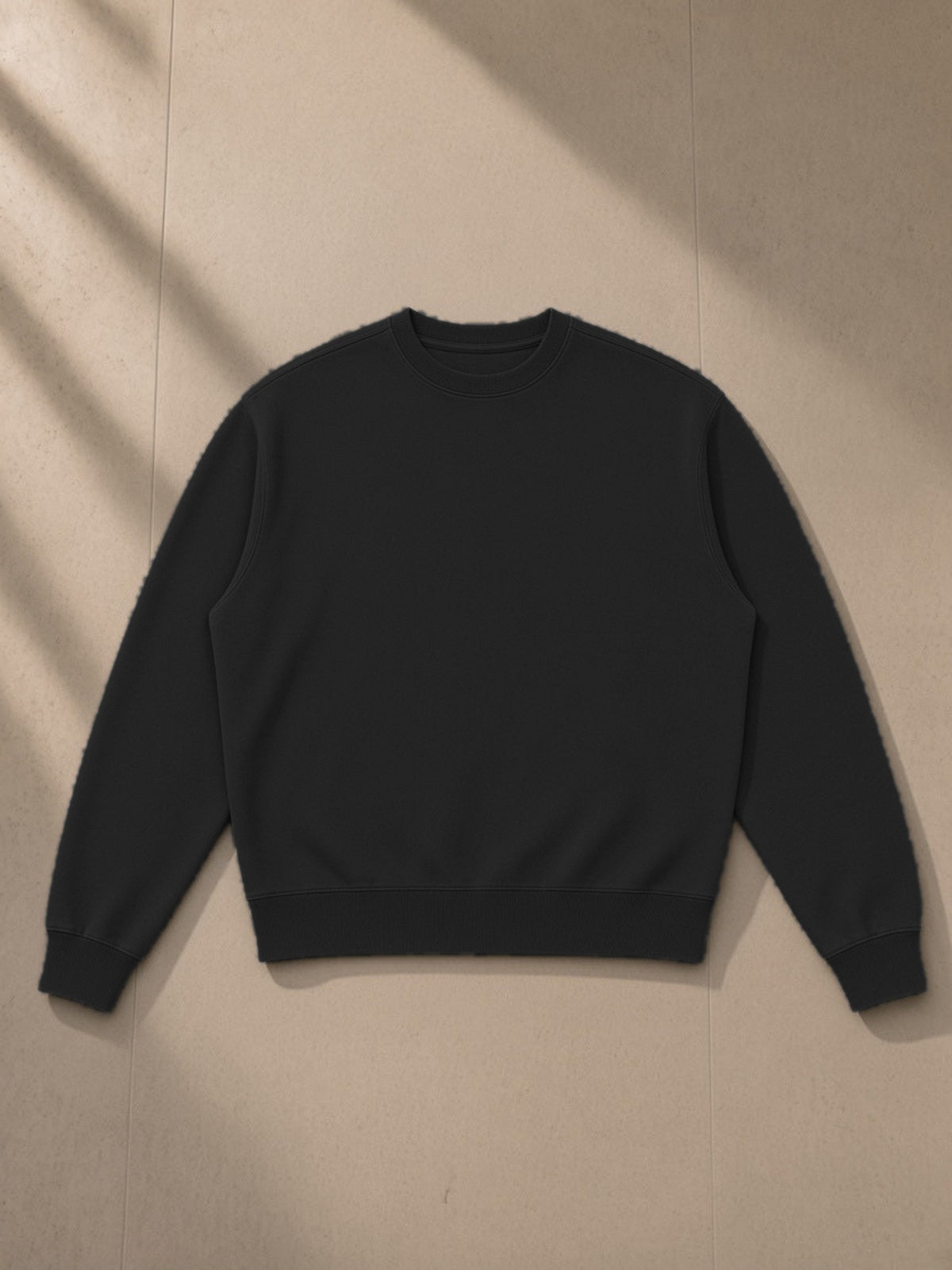 Unisex vintage wash crewneck sweatshirt in Black, laid flat on pale limestone, front view
