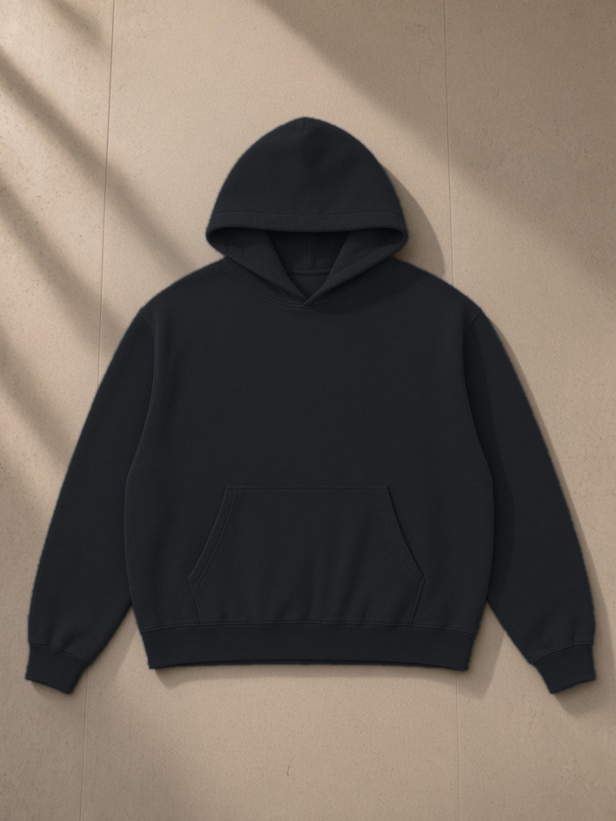 Heavyweight Vintage Wash Boxy Hoodie in Black, laid flat on pale limestone, front view