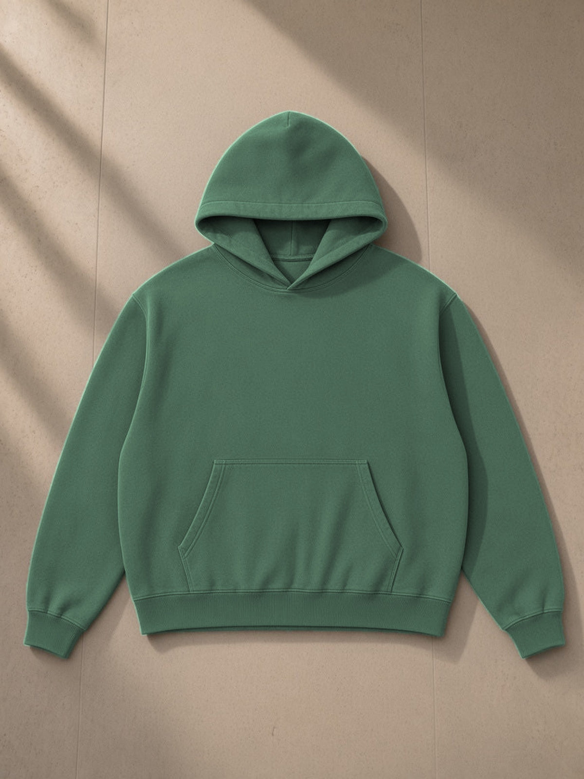 Heavyweight Vintage Wash Boxy Hoodie in Blackish Green, laid flat on pale limestone, front view