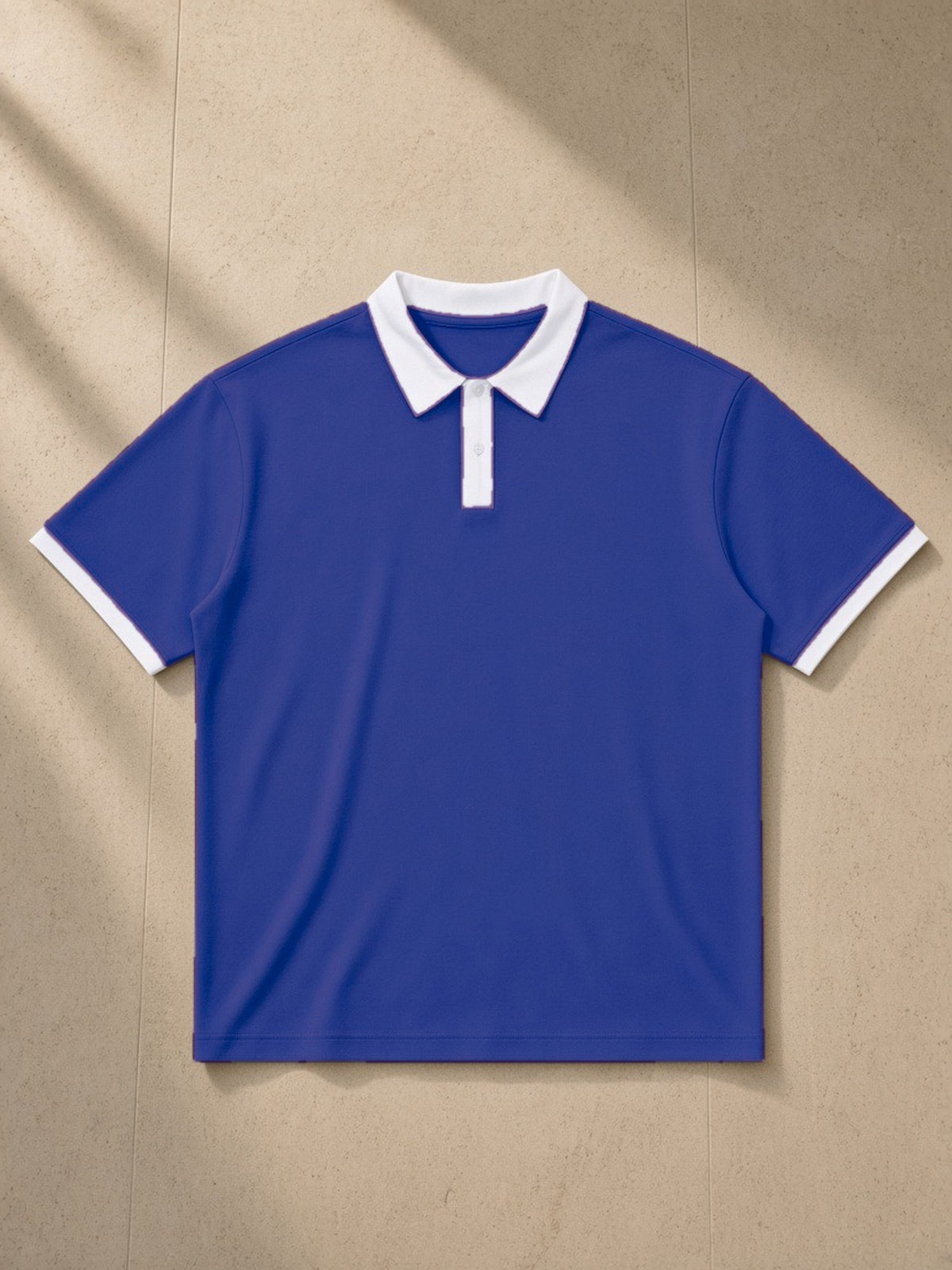 Color Block Polo Shirt in Klein Blue with White, laid flat on pale limestone, front view