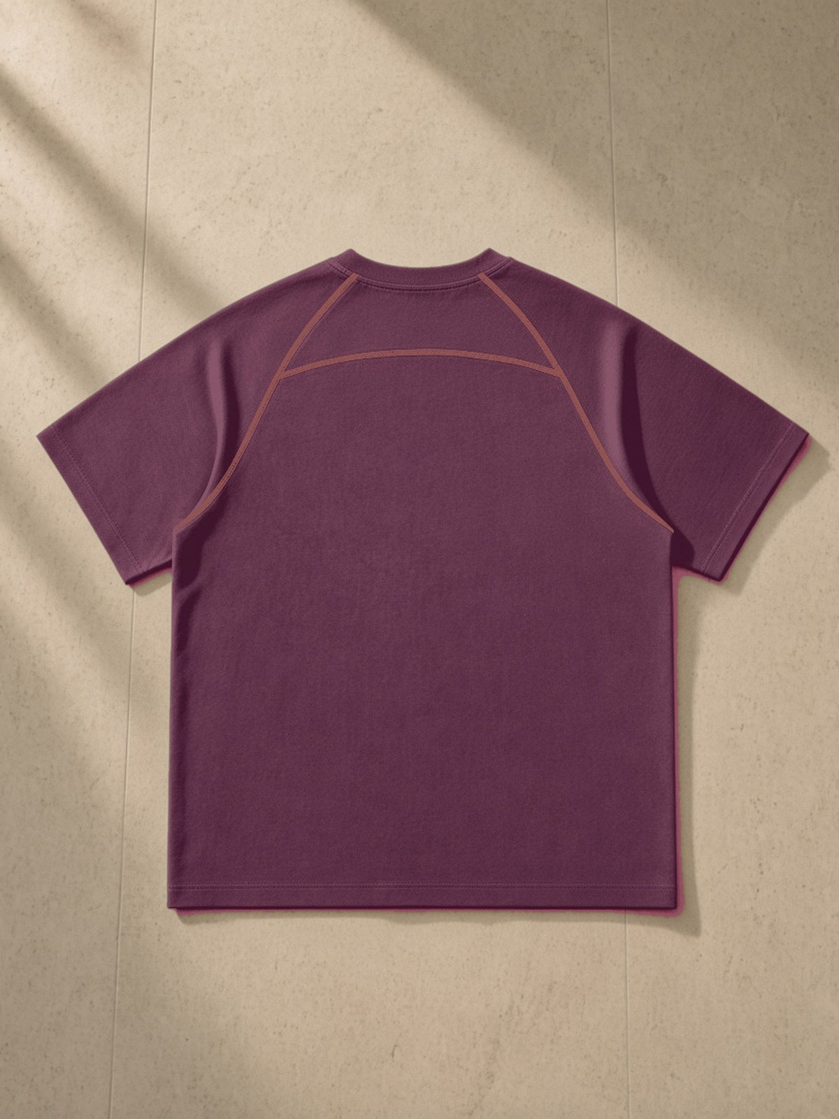 Contrast Stitch Raglan T-Shirt in Plum Purple, laid flat on pale limestone, back view