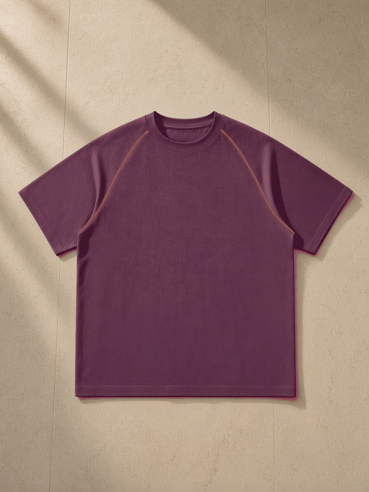Contrast Stitch Raglan T-Shirt in Plum Purple, laid flat on pale limestone, front view