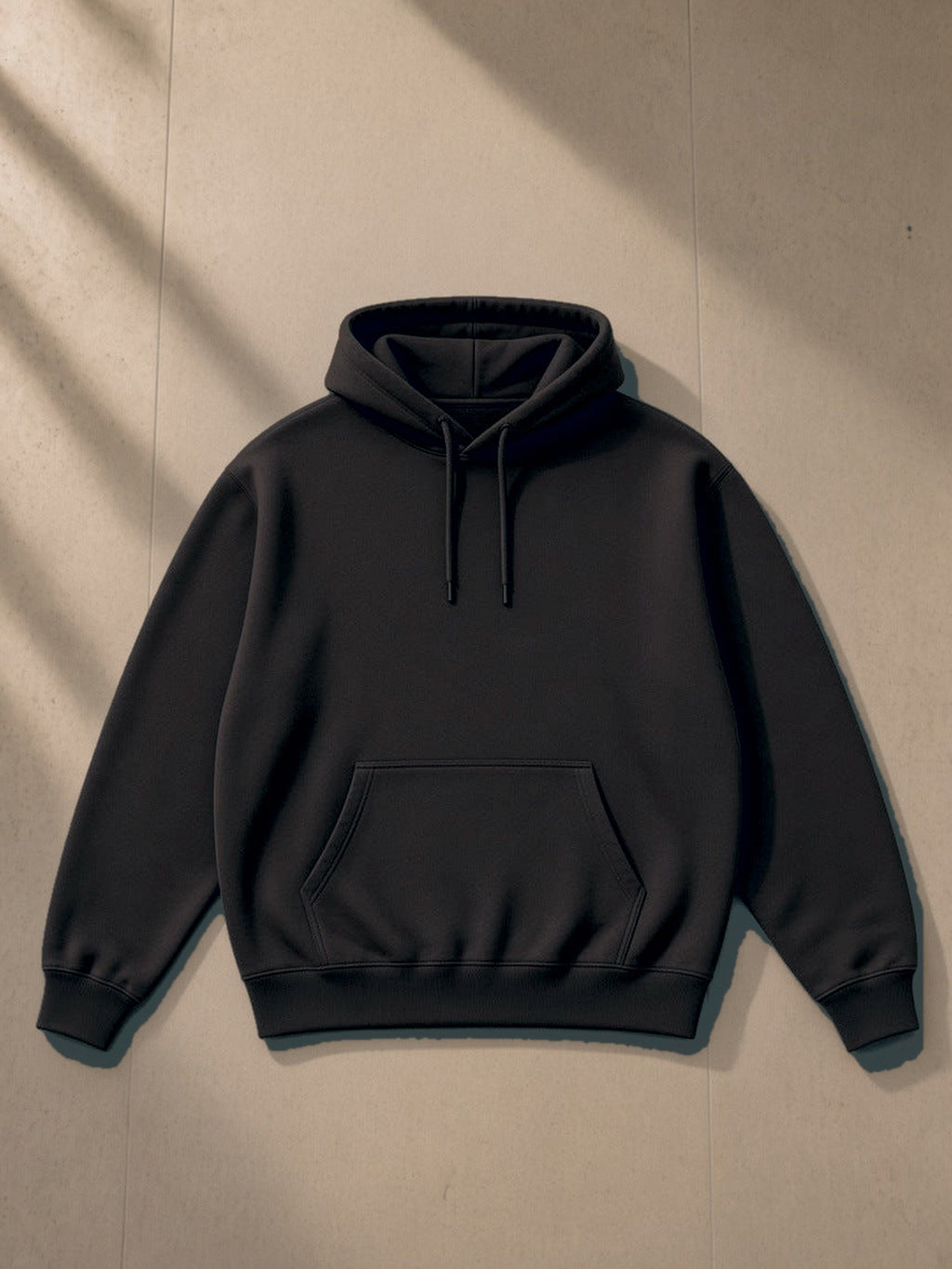 Essential Heavyweight Hoodie in Black, laid flat on pale limestone, front view