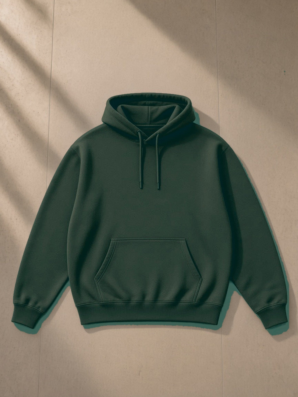 Essential Heavyweight Hoodie in Blackish Green, laid flat on pale limestone, front view