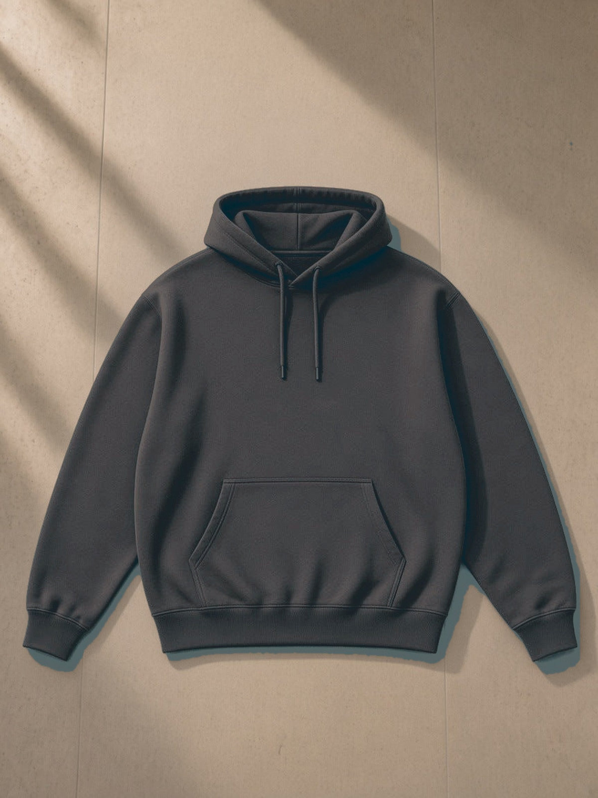 Essential Heavyweight Hoodie in Dark Gray, laid flat on pale limestone, front view