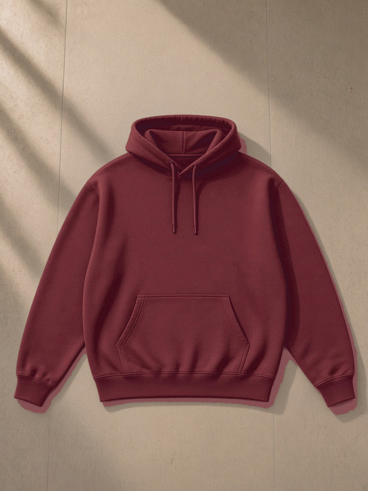 Essential Heavyweight Hoodie in Dull Red, laid flat on pale limestone, front view