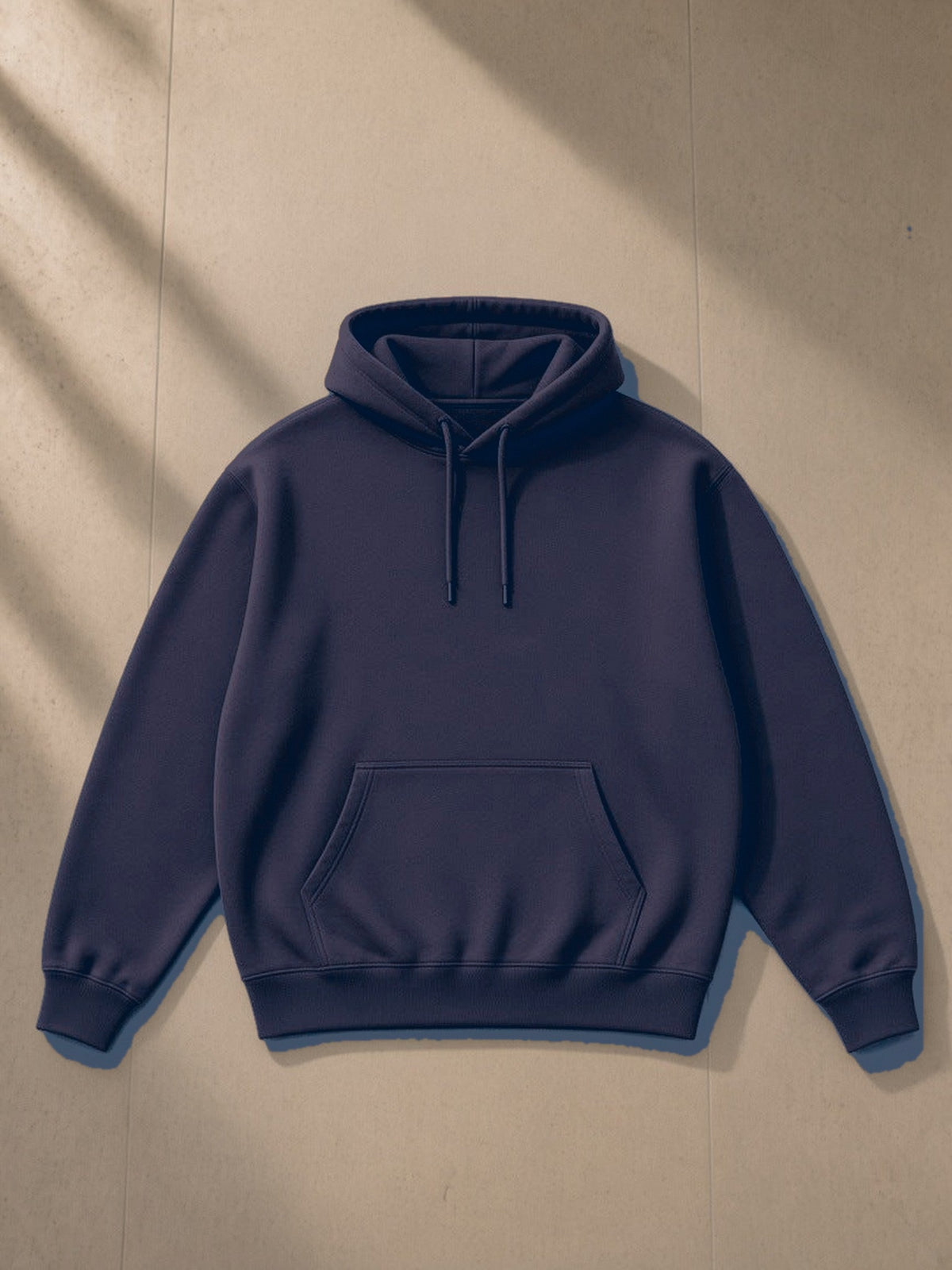 Essential Heavyweight Hoodie in Navy Blue, laid flat on pale limestone, front view