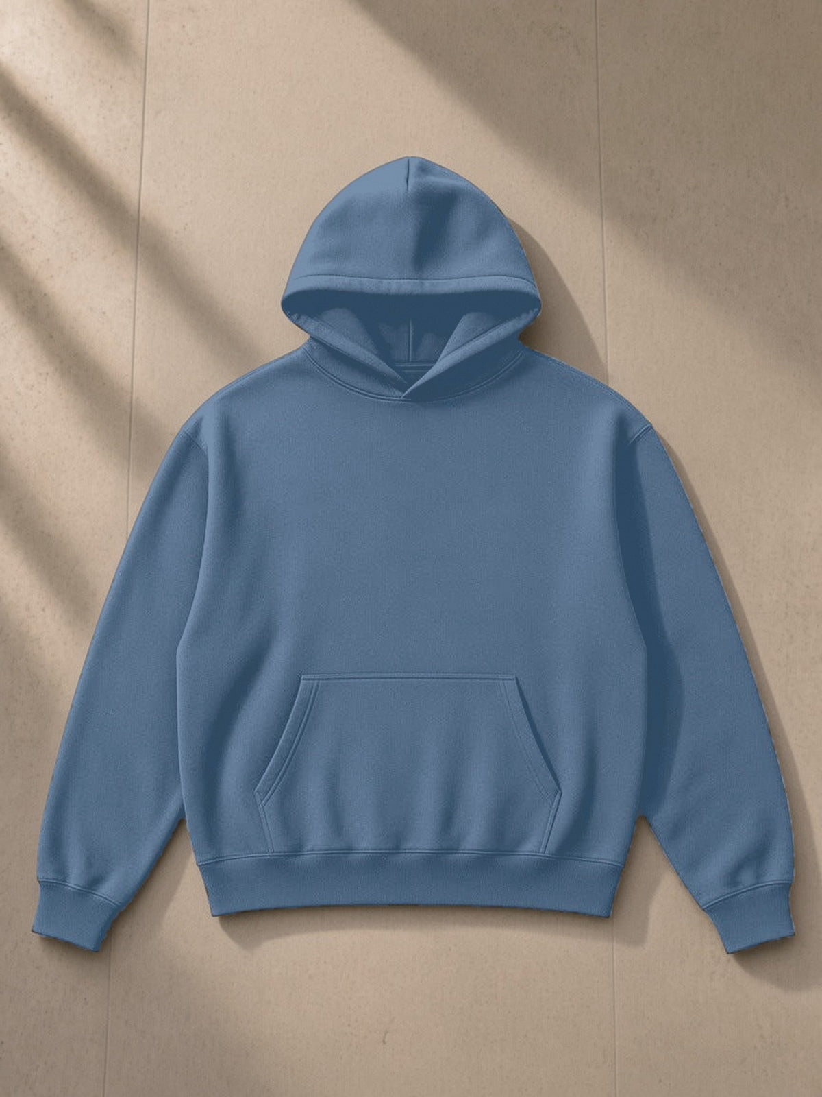 Drop Shoulder Hoodie in Haze Blue, laid flat on pale limestone, front view